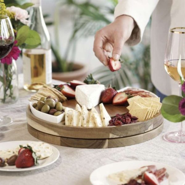 Hand Picking Up Food Off Of Rotating Charcuterie Tray Filled With Cheese, Fruits And Meats